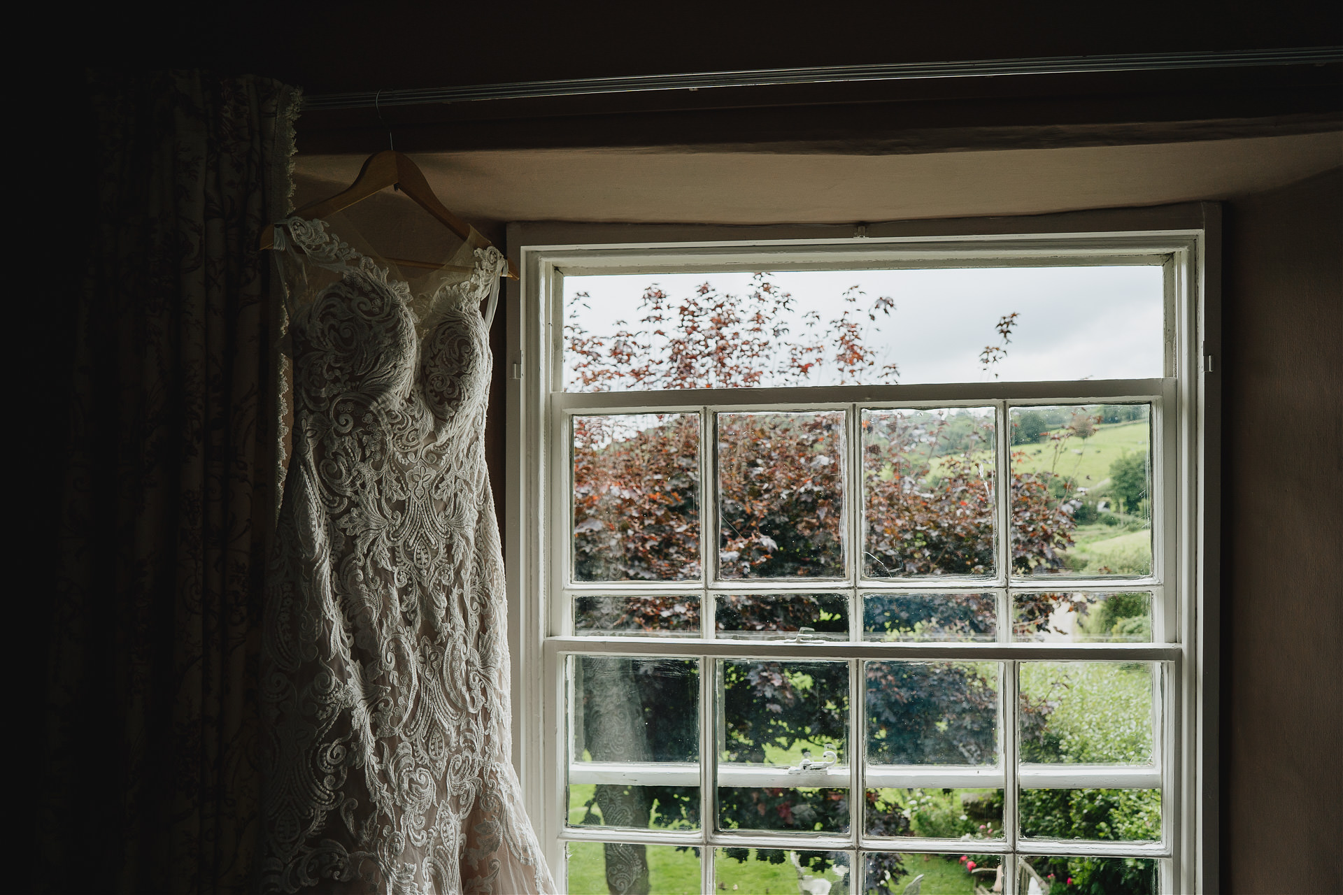 Wedding dress hanging up in a window with amazing country views outside