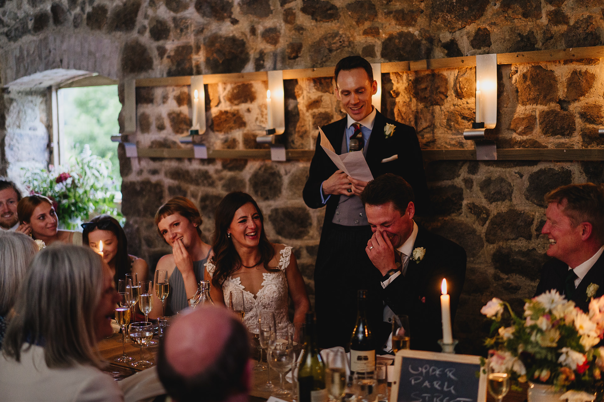 Best man speech in a beautiful wedding barn with candles lit around the stone walls