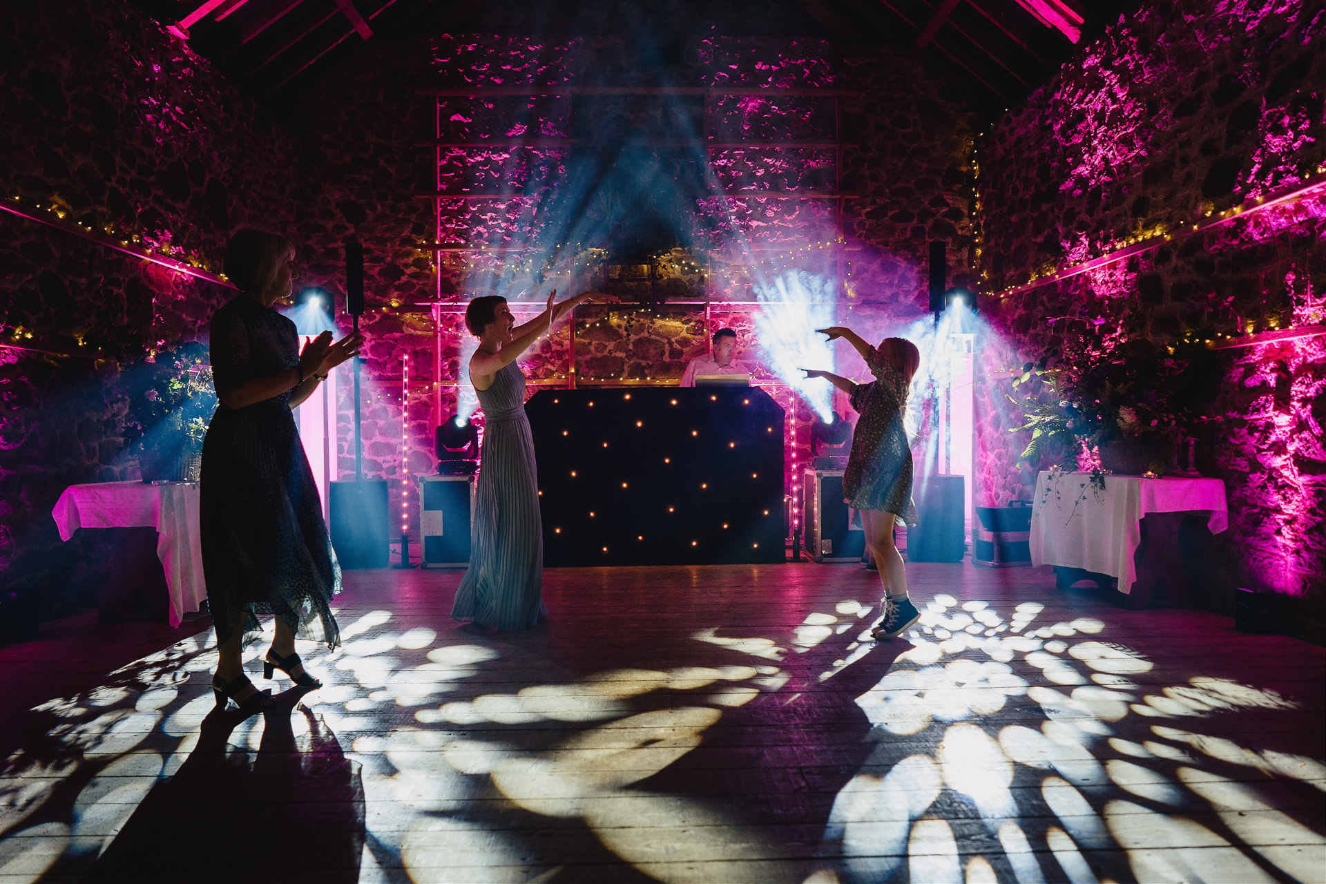 People dancing in front of incredible DJ light display in wow factor wedding barn