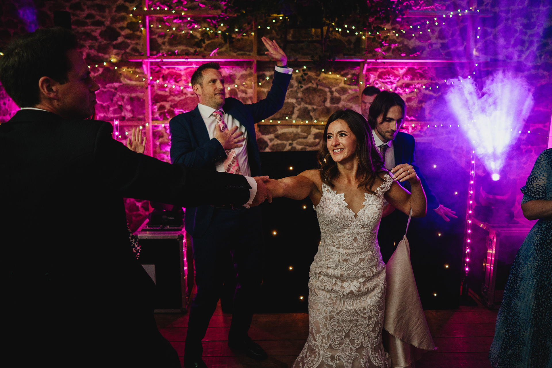 Bride and groom dancing together in amazing lit wedding barn