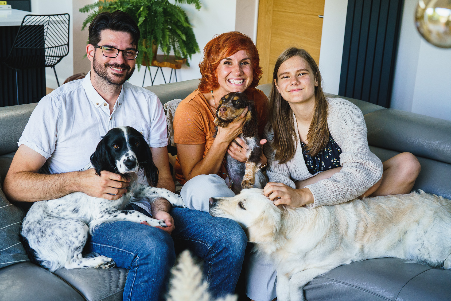 A family photo with two adults and a teenage girl, and three dogs