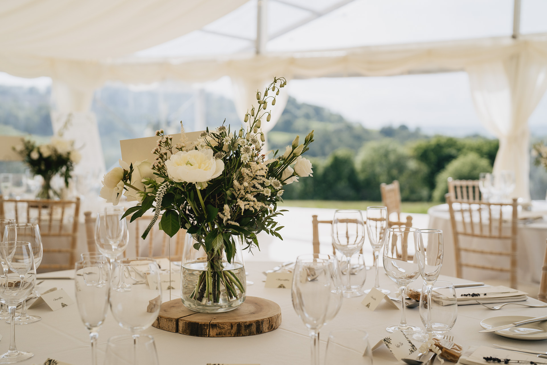 Wedding table decorations in a marquee at River Cottage with views across the fields and valley