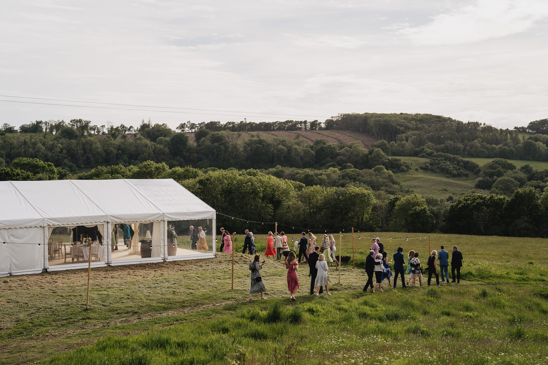 Guests walking through a field to a marquee at a wedding at River Cottage