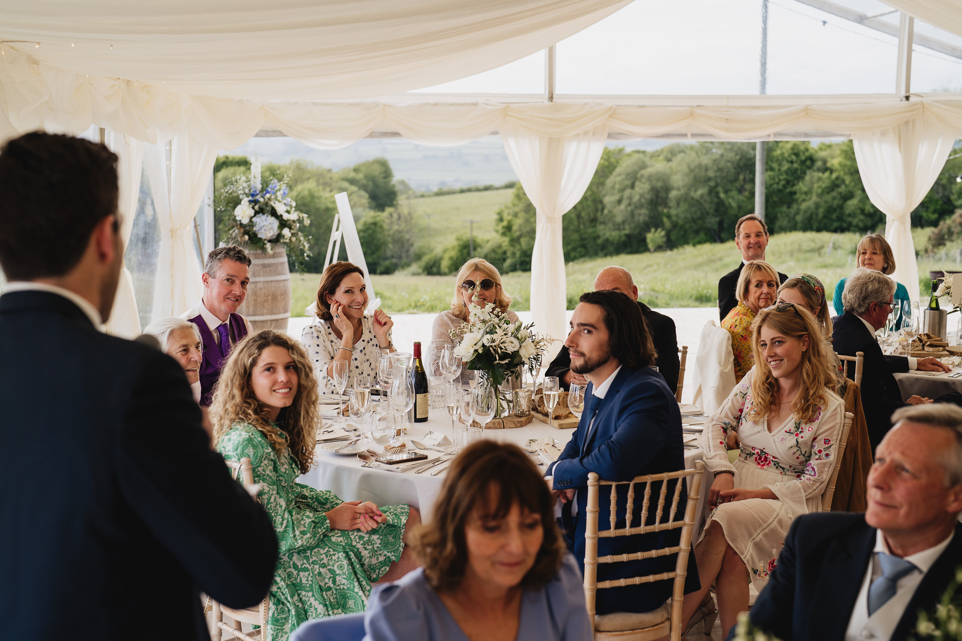Wedding guests reacting during the Groom's speech in a marquee at River Cottage