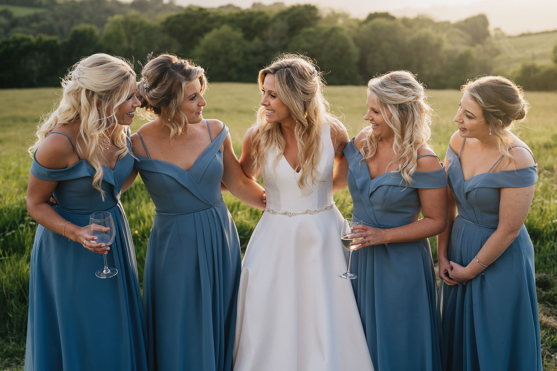 Bride and bridesmaids smiling in the sunshine during a wedding at River Cottage
