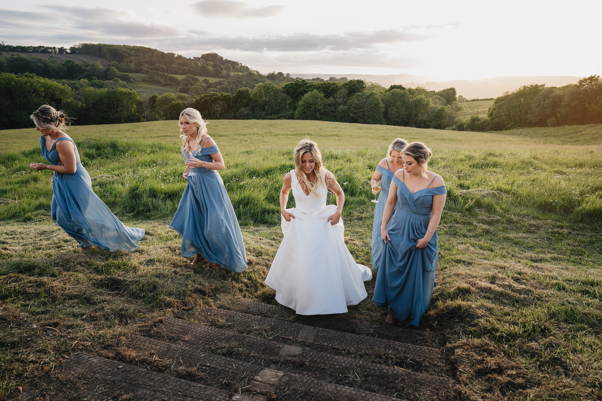Bride and bridesmaids walking across the field at River Cottage