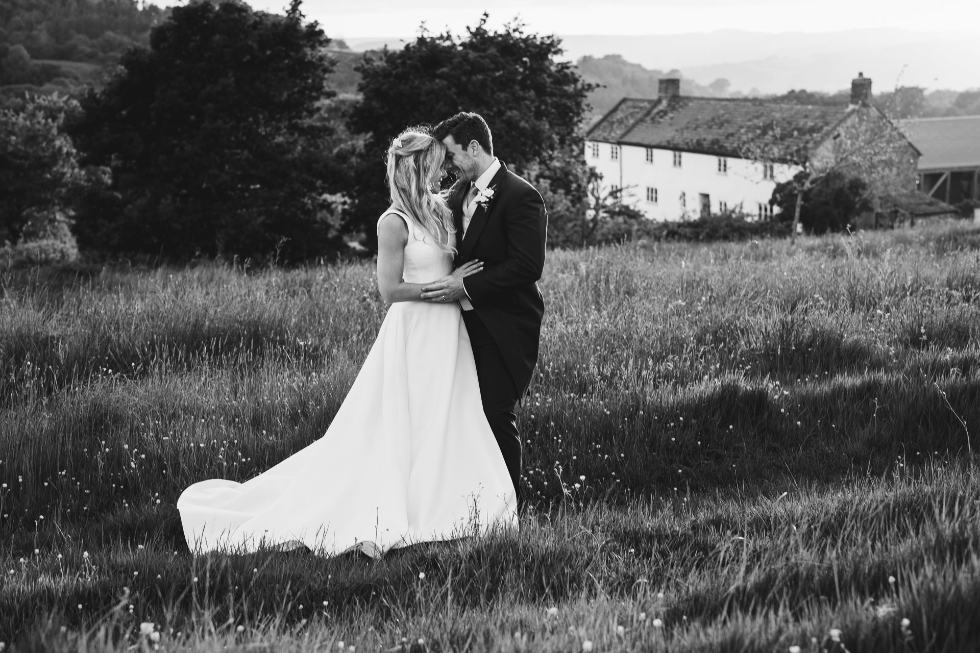 Bride and groom cuddling together on their wedding day with River Cottage behind them