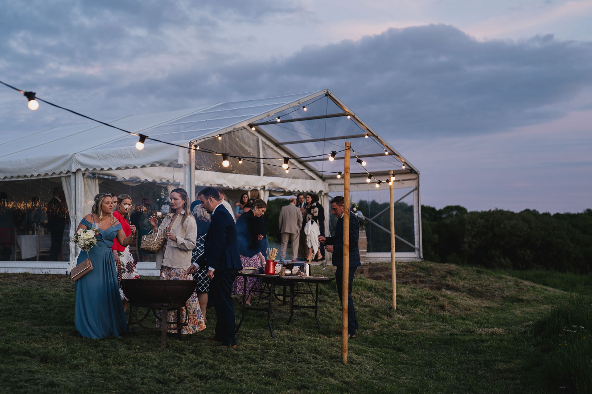 Wedding guests outside a marquee in evening light