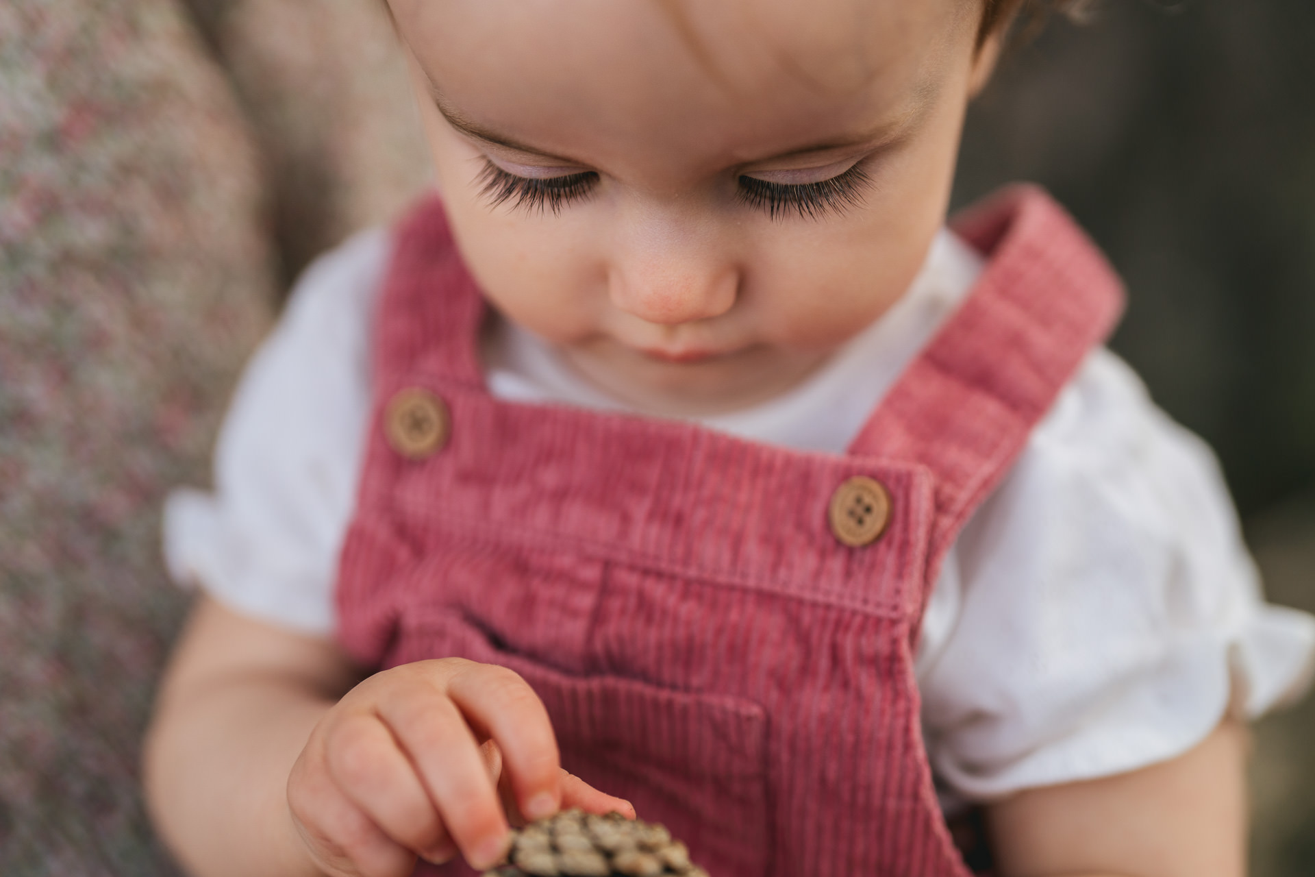 Close up photo of a baby girl in a pink dress with focus on her eyelashes