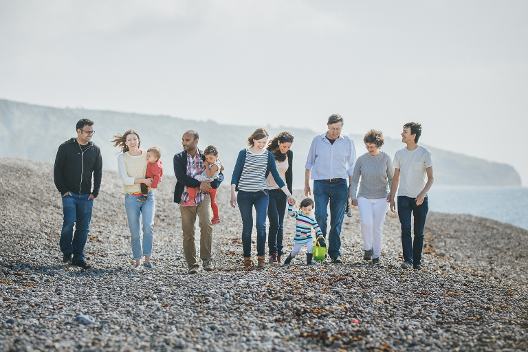 An extended family photograph session on the beach at Beer in Dorset. Extended family walking along the pebbles together, chatting and laughing. 
