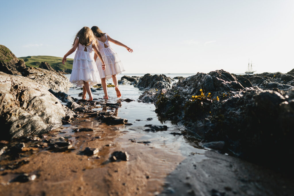 Two young girls paddling on the beach during an evening photography session