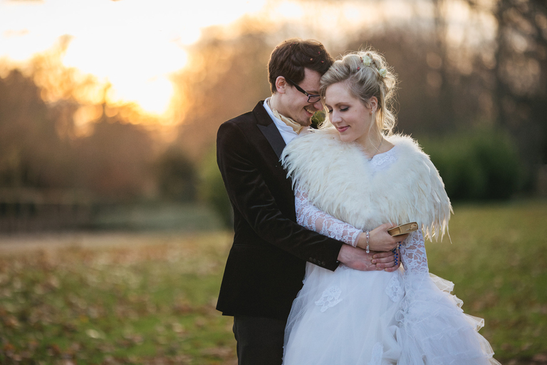 A bride and groom cuddling in December sunlight at a winter wedding in Somerset