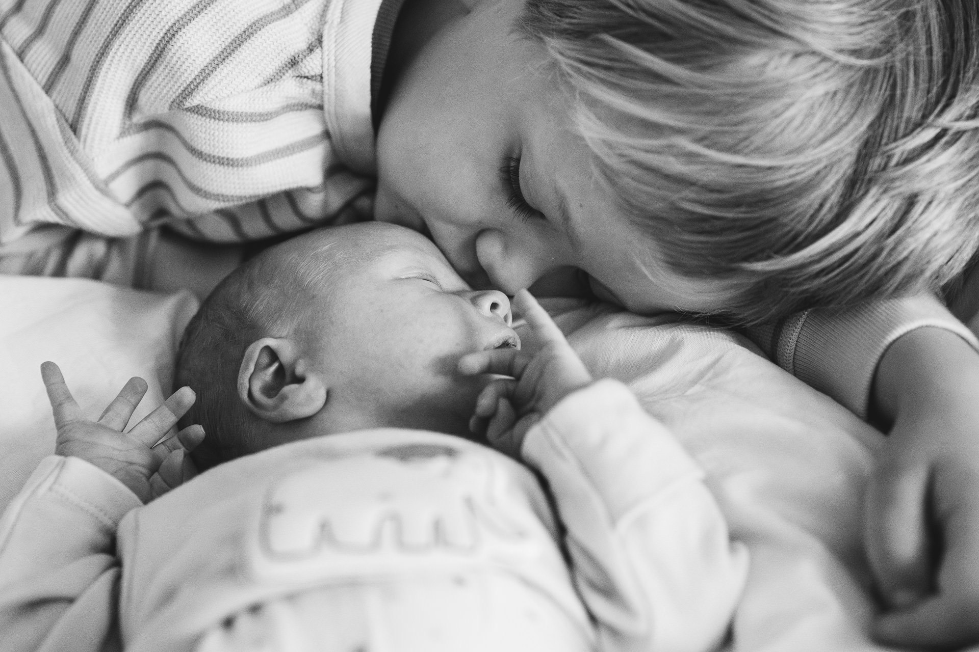 A young boy snuggling up to a baby in a Devon newborn photo session 