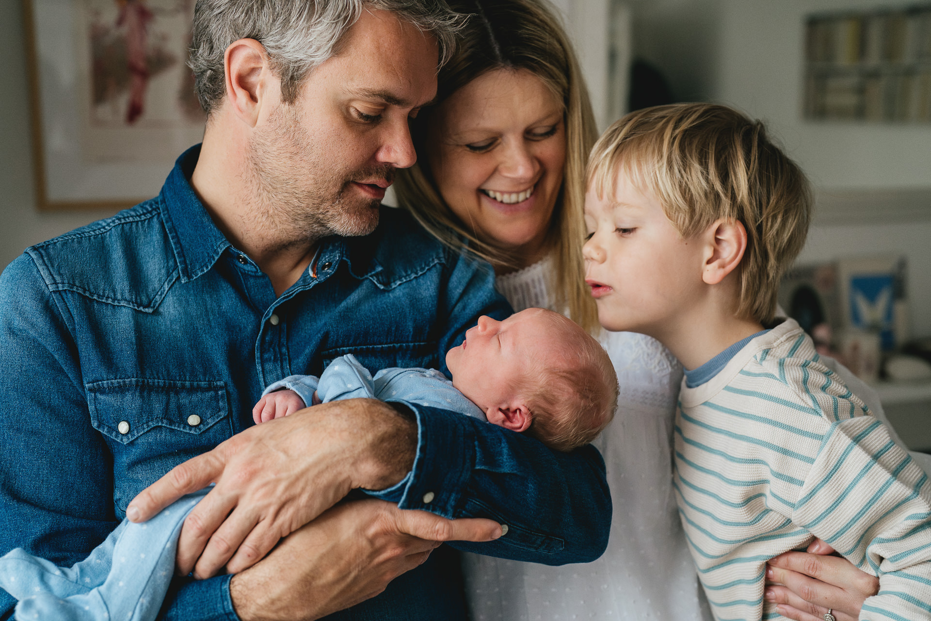 A family together looking at a newborn baby during a photo session at home