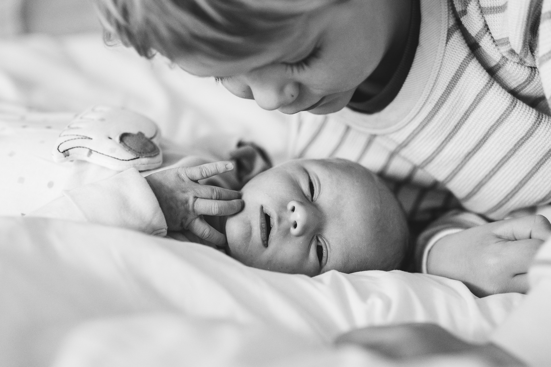 An older brother looking at a newborn baby during a photography session