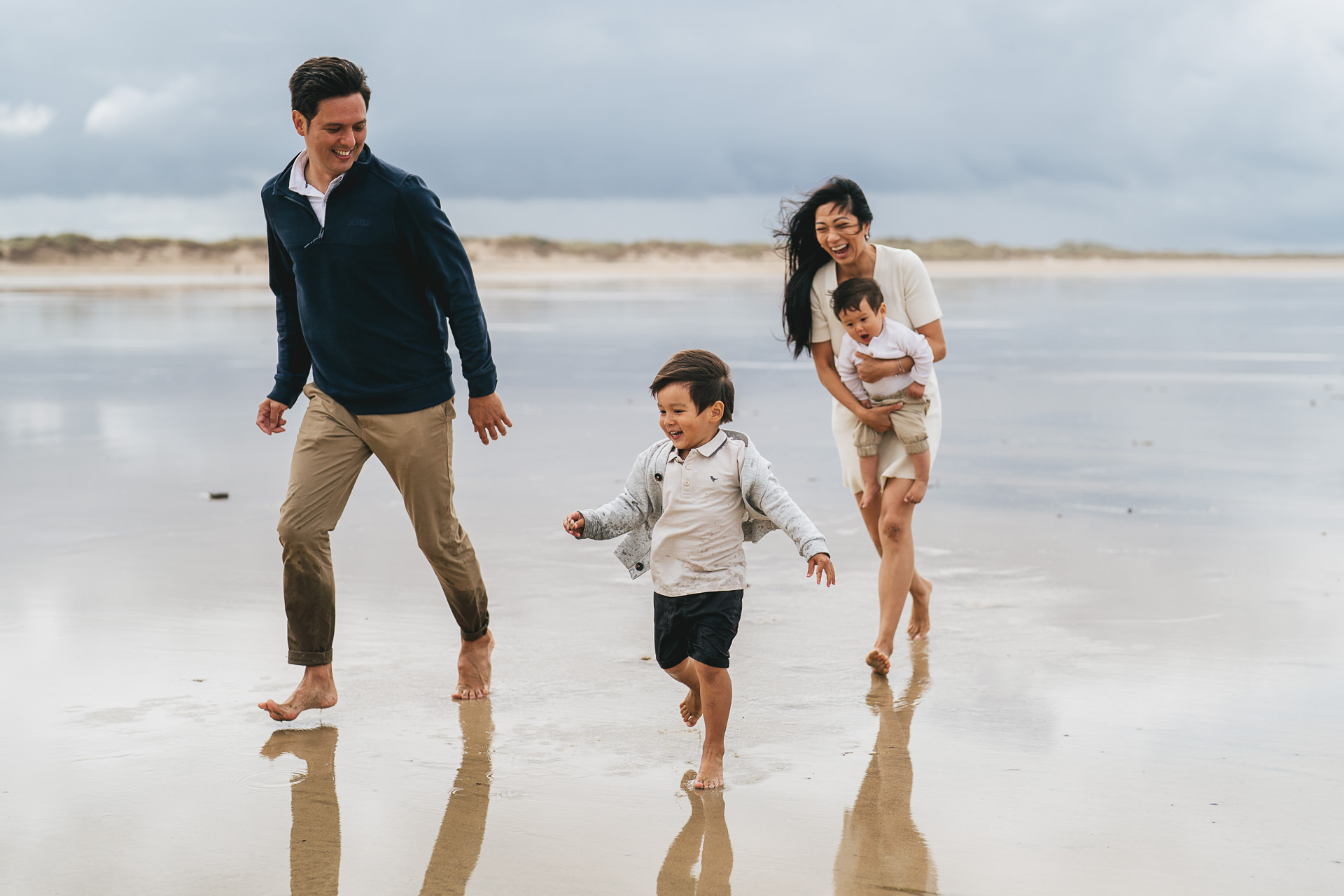 A family playing together, running on the sand in North Devon during a family photography session