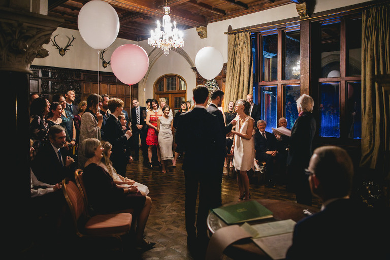 A winter wedding ceremony after dark, in the main entrance hall at Huntsham Court in Devon