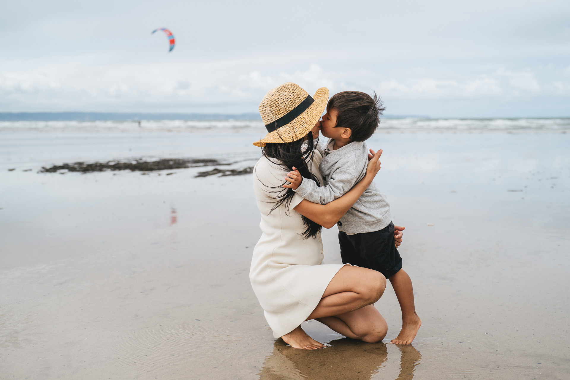 A young boy kissing his mother at the beach during a family photography session at Saunton Sands