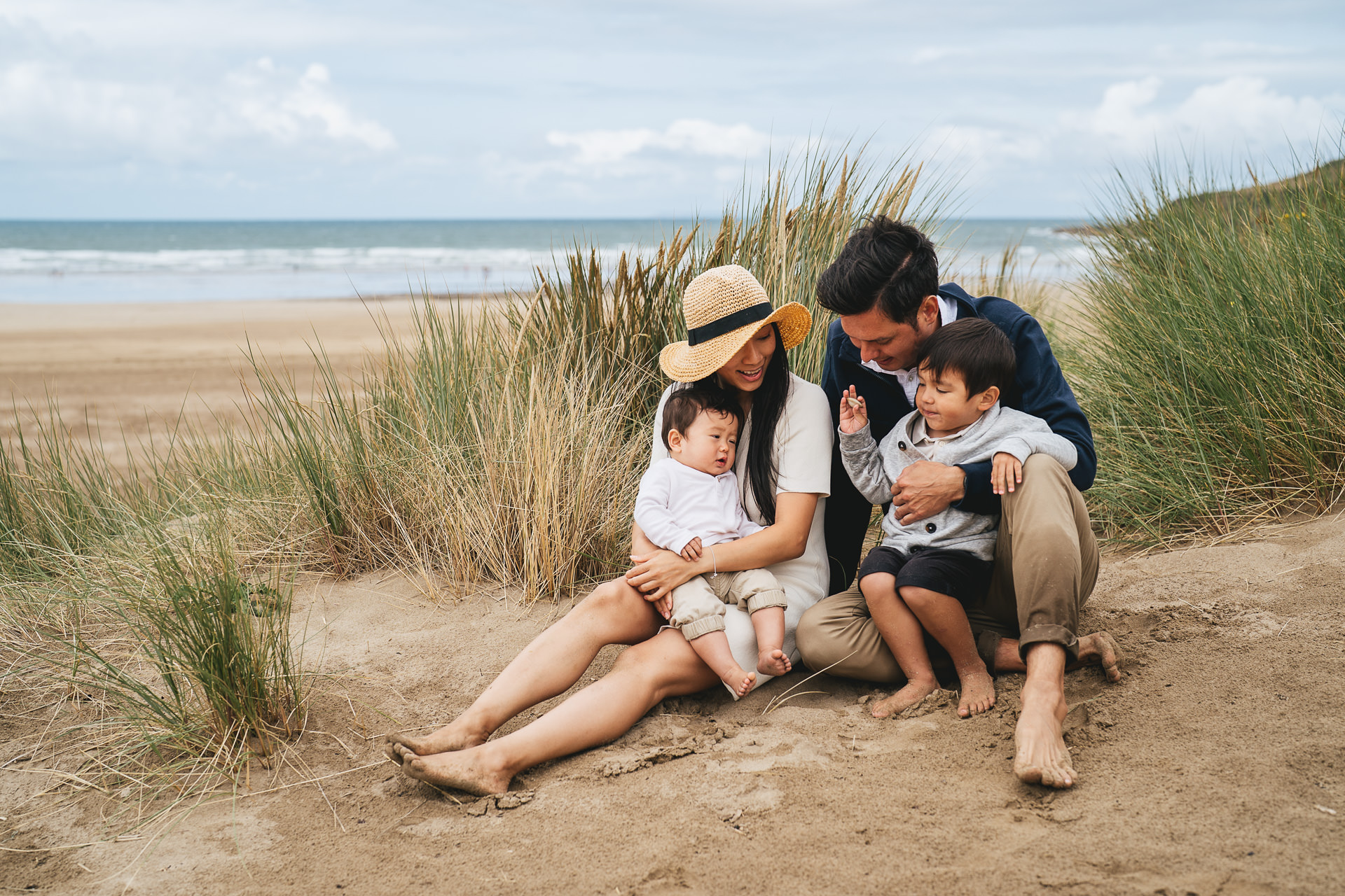 A group photo of a family sitting in the sand dunes together during a family photography session in North Devon