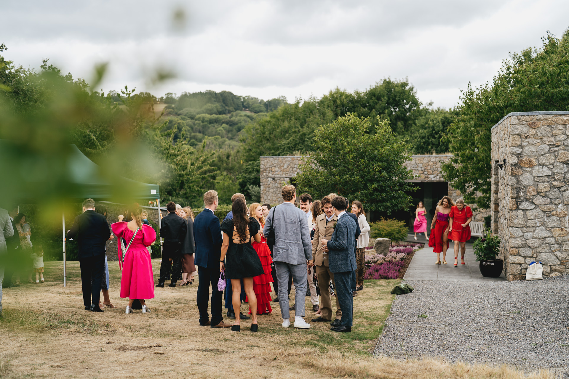 Wedding guests at a drinks reception outside a stylish house with Dartmoor views behind
