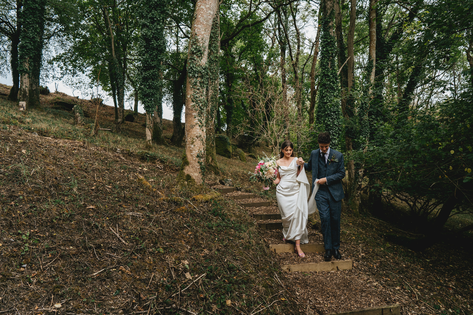 A stylish bride and groom walking down steps in Dartmoor woods