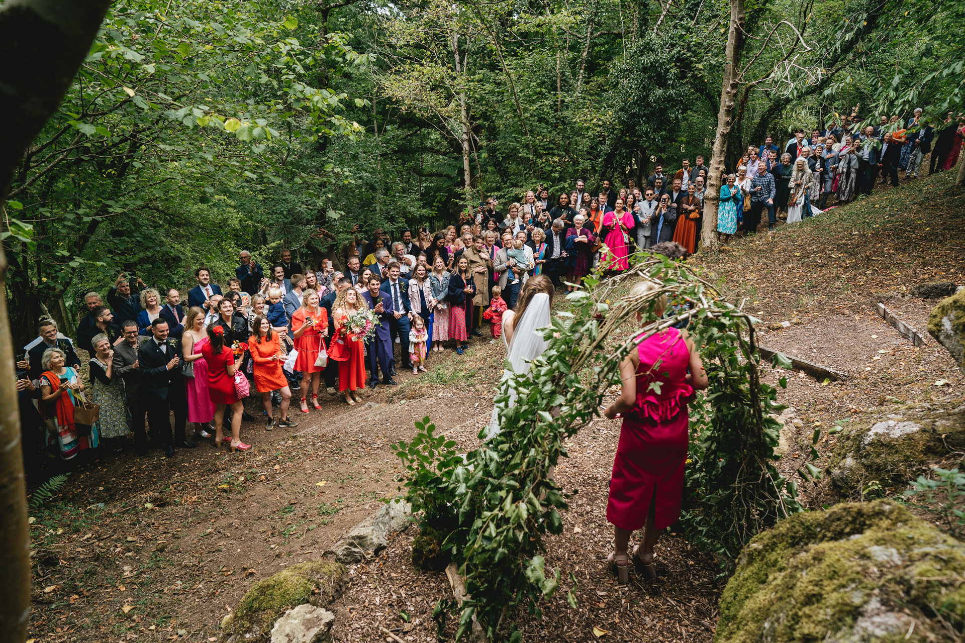 A large wedding crowd standing in woodland at an outdoor wedding ceremony on Dartmoor