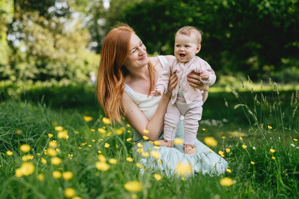 A mother and baby sitting in grass together during a summer family photography session