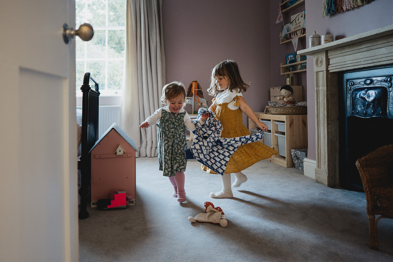 Two young girls running around in their bedroom while getting ready for a family photography session