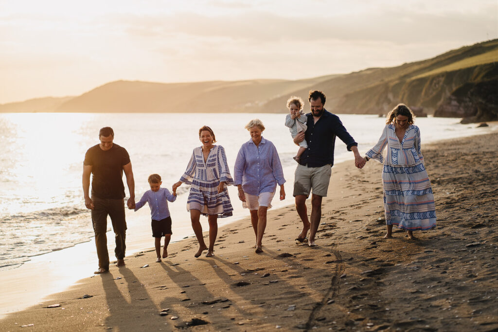 An extended family group walking along the beach together during a family photography session in Cornwall