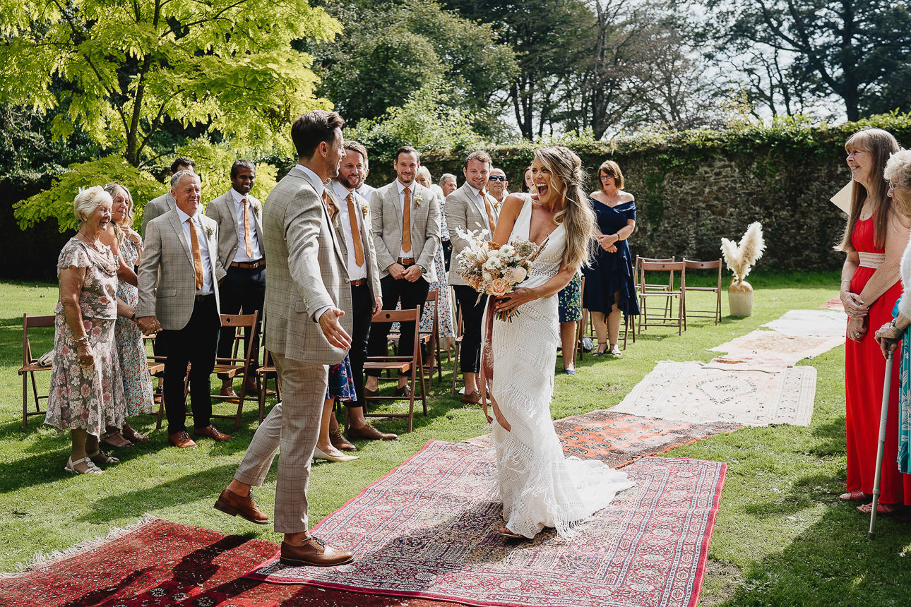 A bride and groom seeing each other for the first time with huge smiles at a boho outdoor wedding ceremony