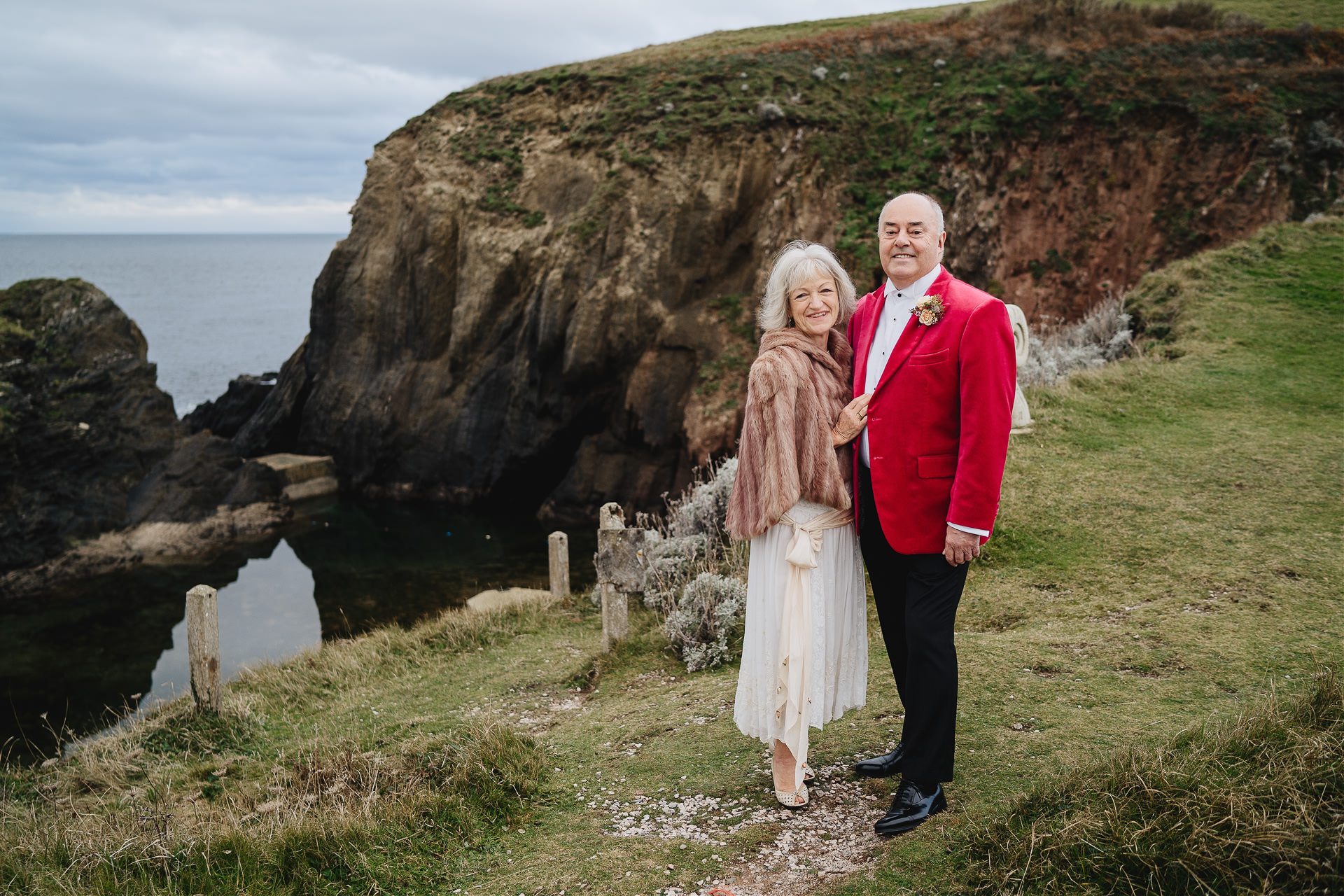 A stylish bride and groom standing by the mermaid pool at Burgh Island Hotel