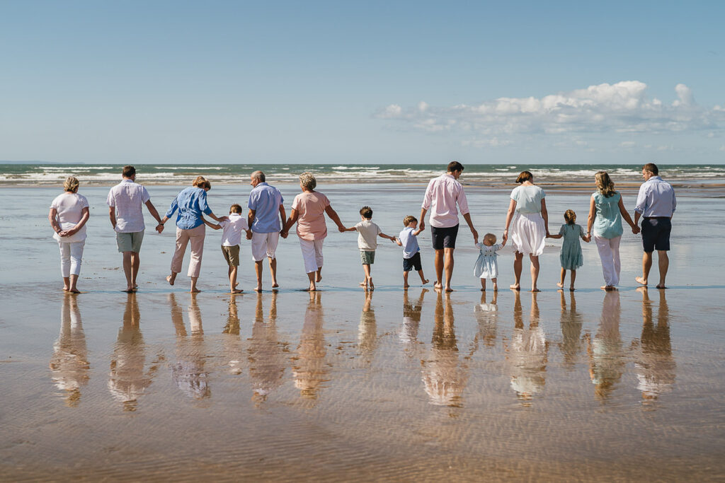 A large extended family group walking hand in hand across the sand on a north Devon beach