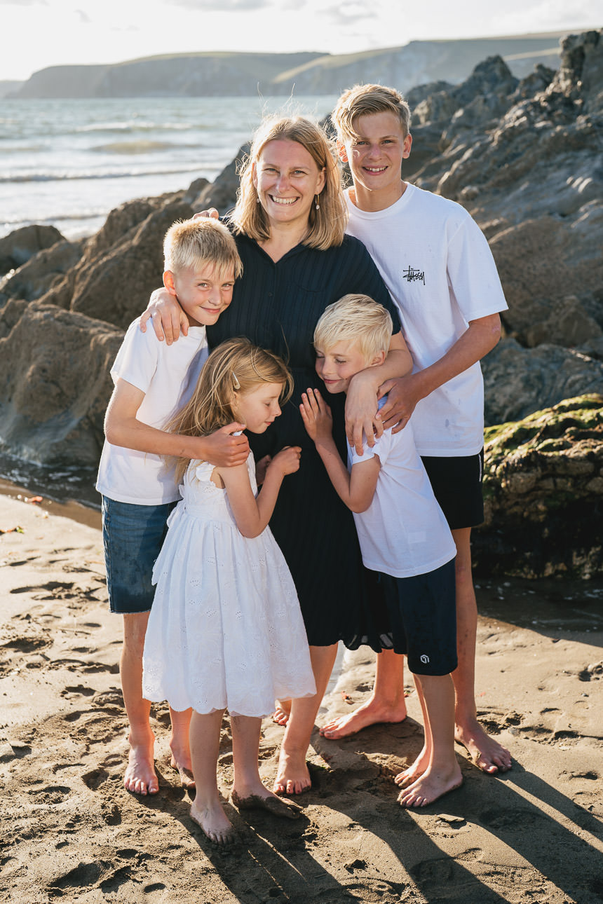 Group shot of a mother with four children, standing on the sand on a Devon beach