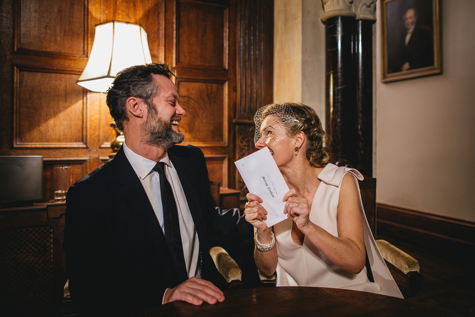 A bride and groom just married, smiling with their marriage certificate at Huntsham Court
