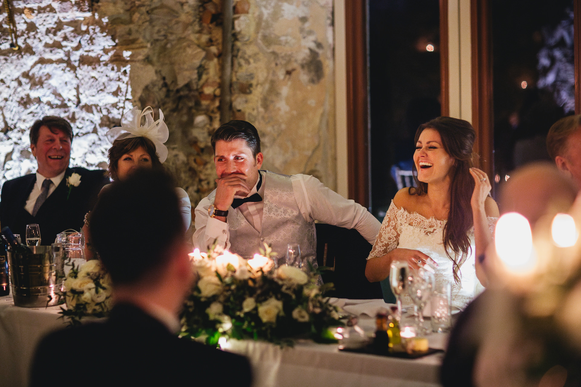 A bride and groom laughing at wedding speeches at Lulworth Castle in Dorset