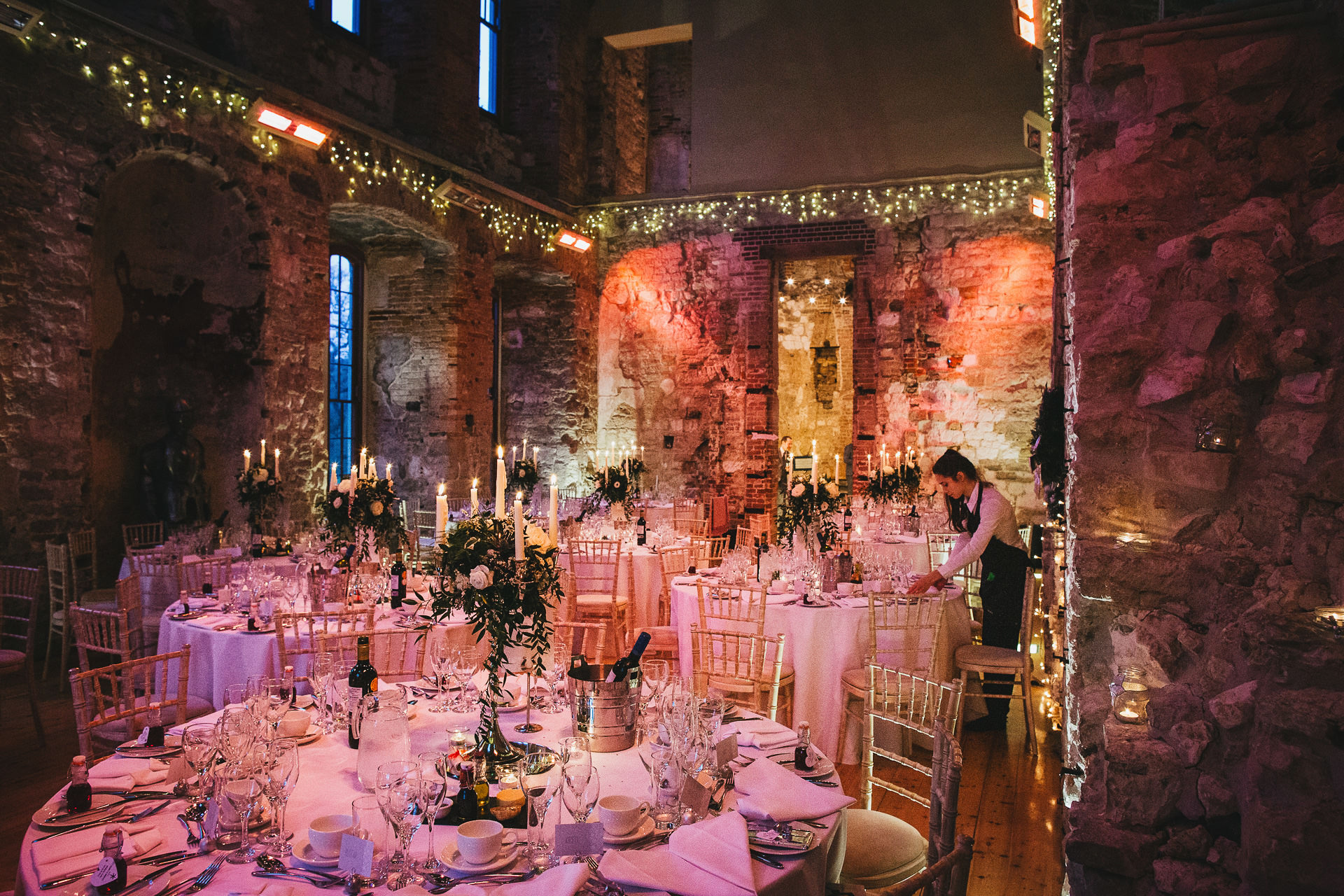 Lulworth Castle decorated for a winter wedding, with candles, fairy lights and pink lighting