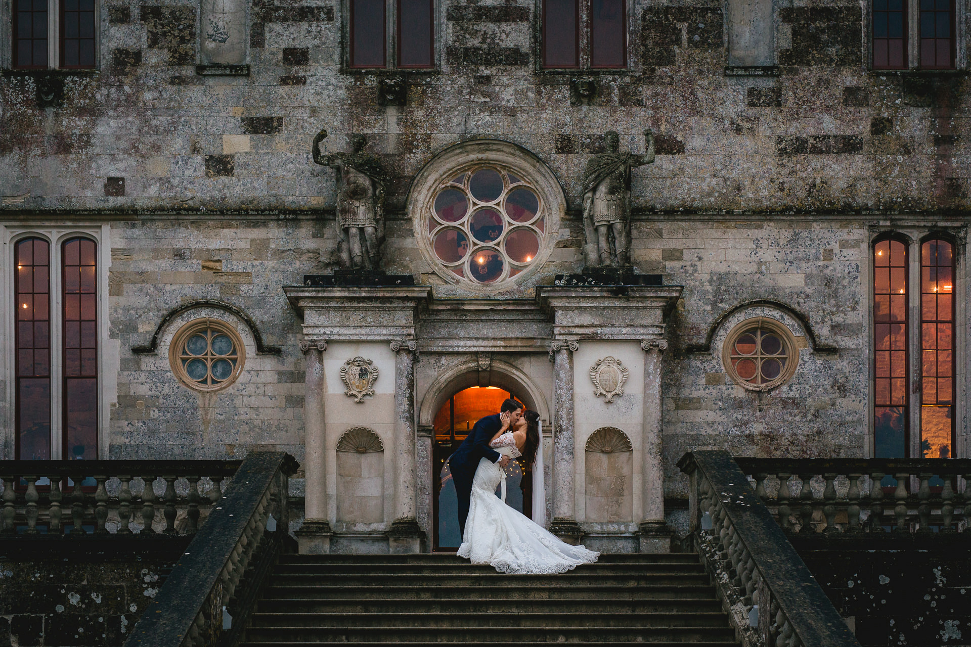A bride and groom kissing on the steps of Lulworth Castle