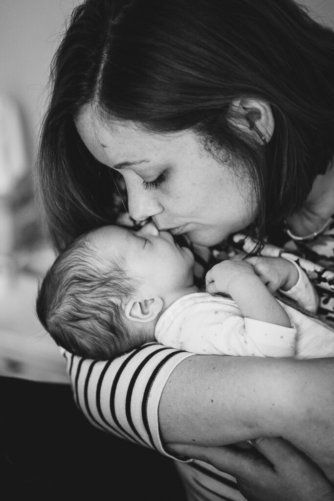 A mum gently kissing a newborn baby