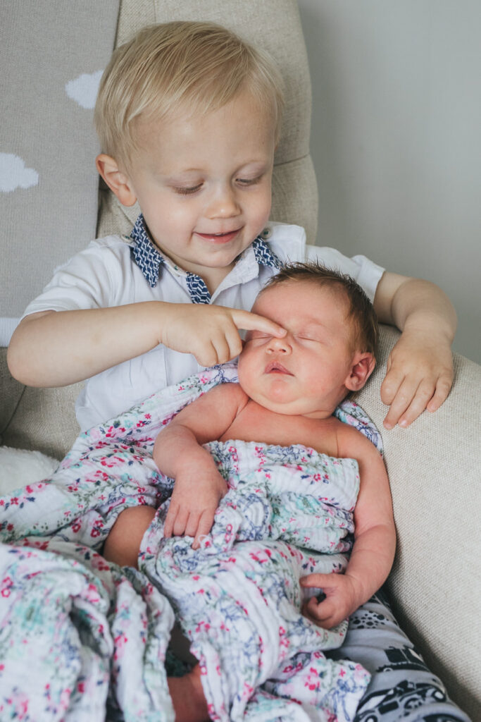 A newborn baby with older brother sitting on a chair together