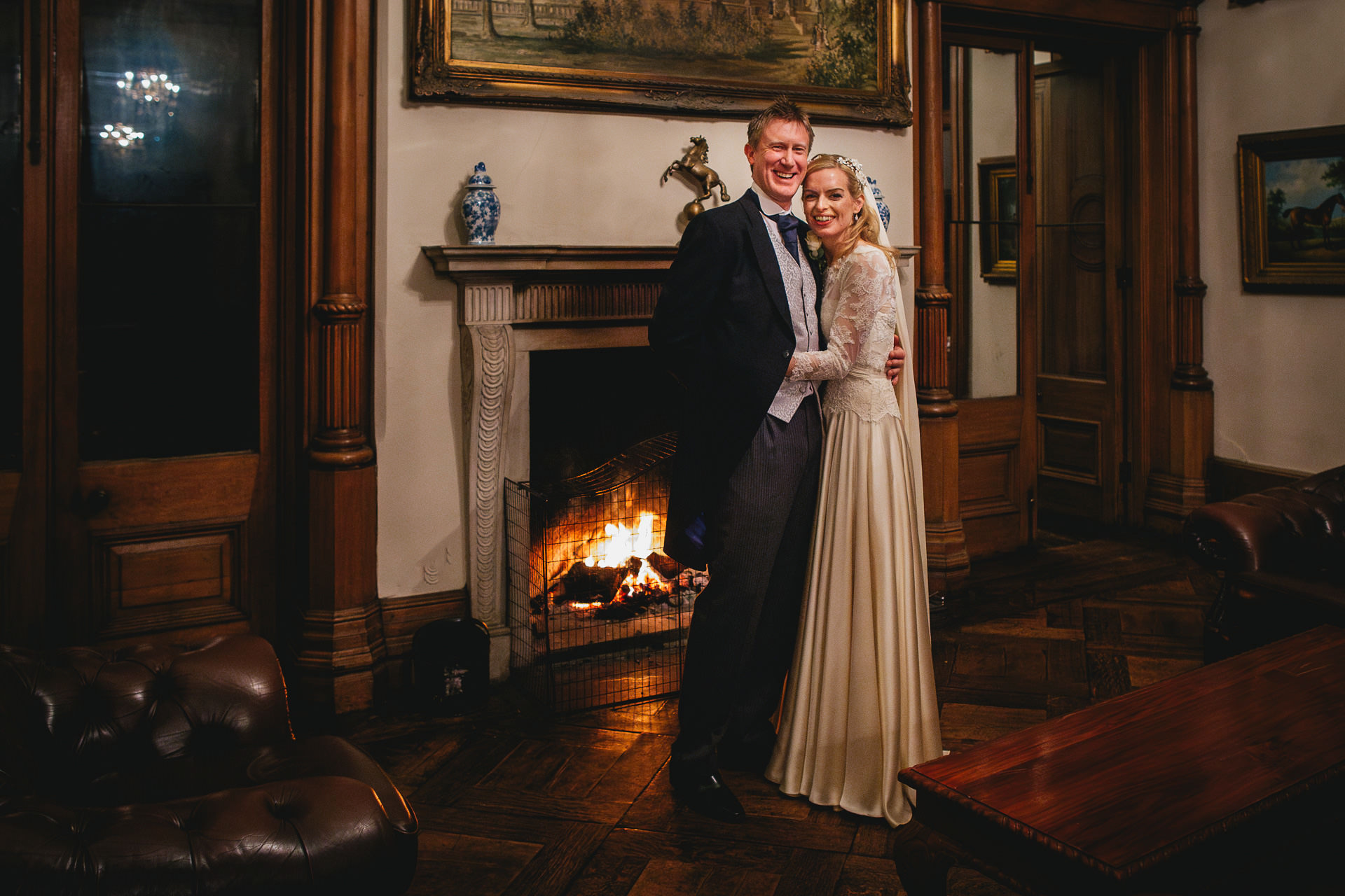 A bride and groom by a fireplace at a winter wedding at Orchardleigh in Somerset