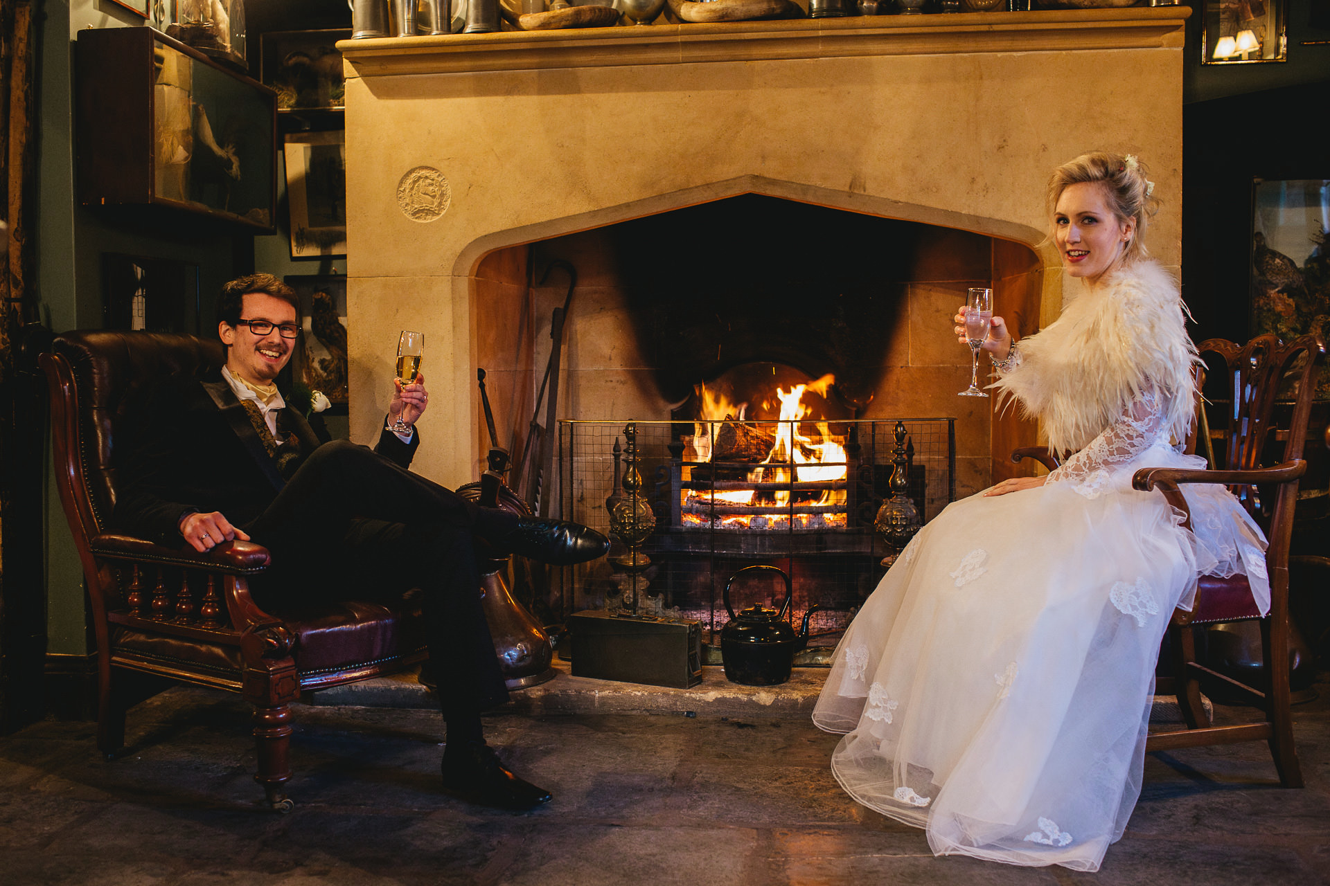 A bride and groom sitting by a log fire during their winter wedding celebration