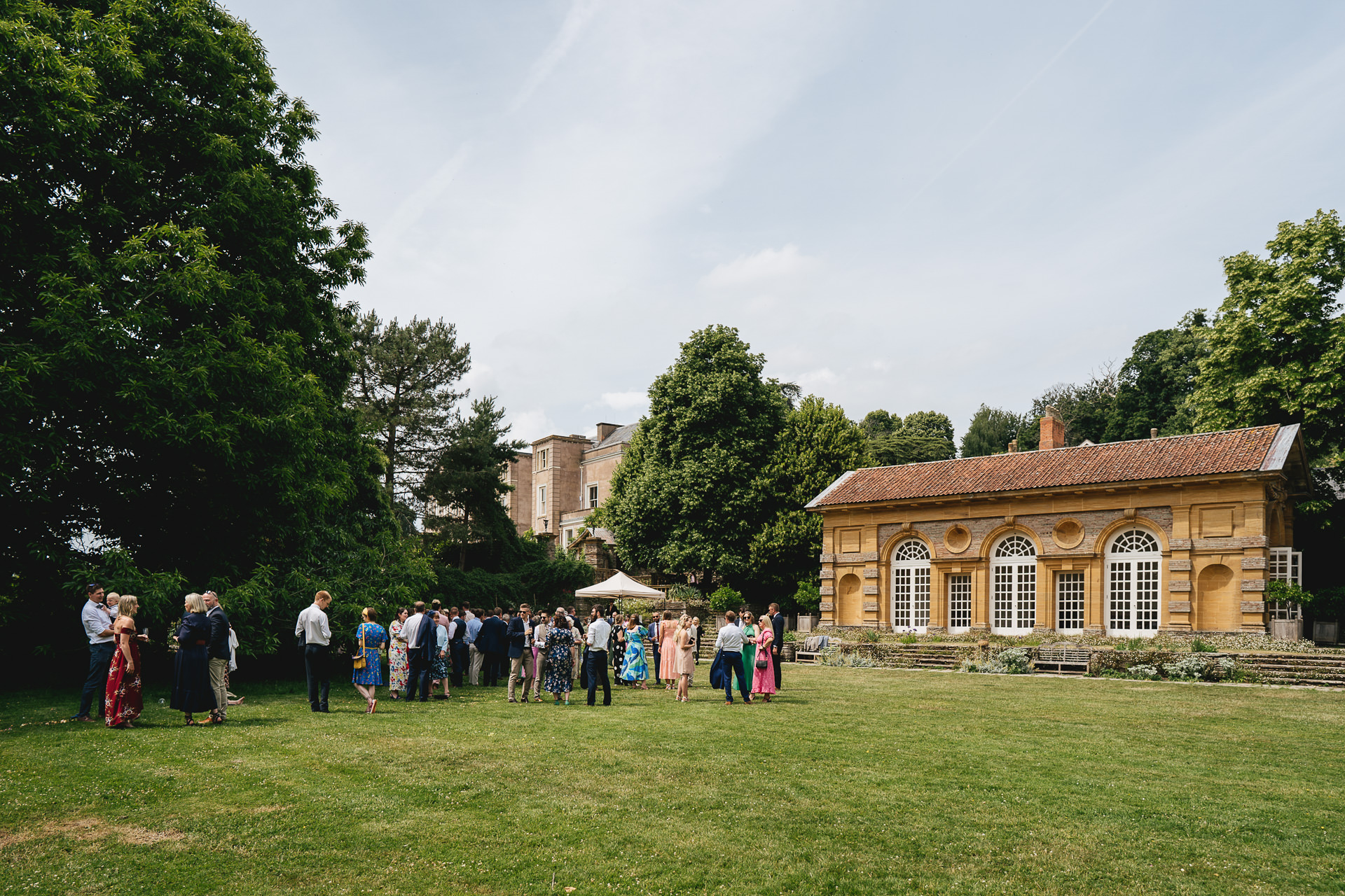 Wedding guests having drinks outside an orangery