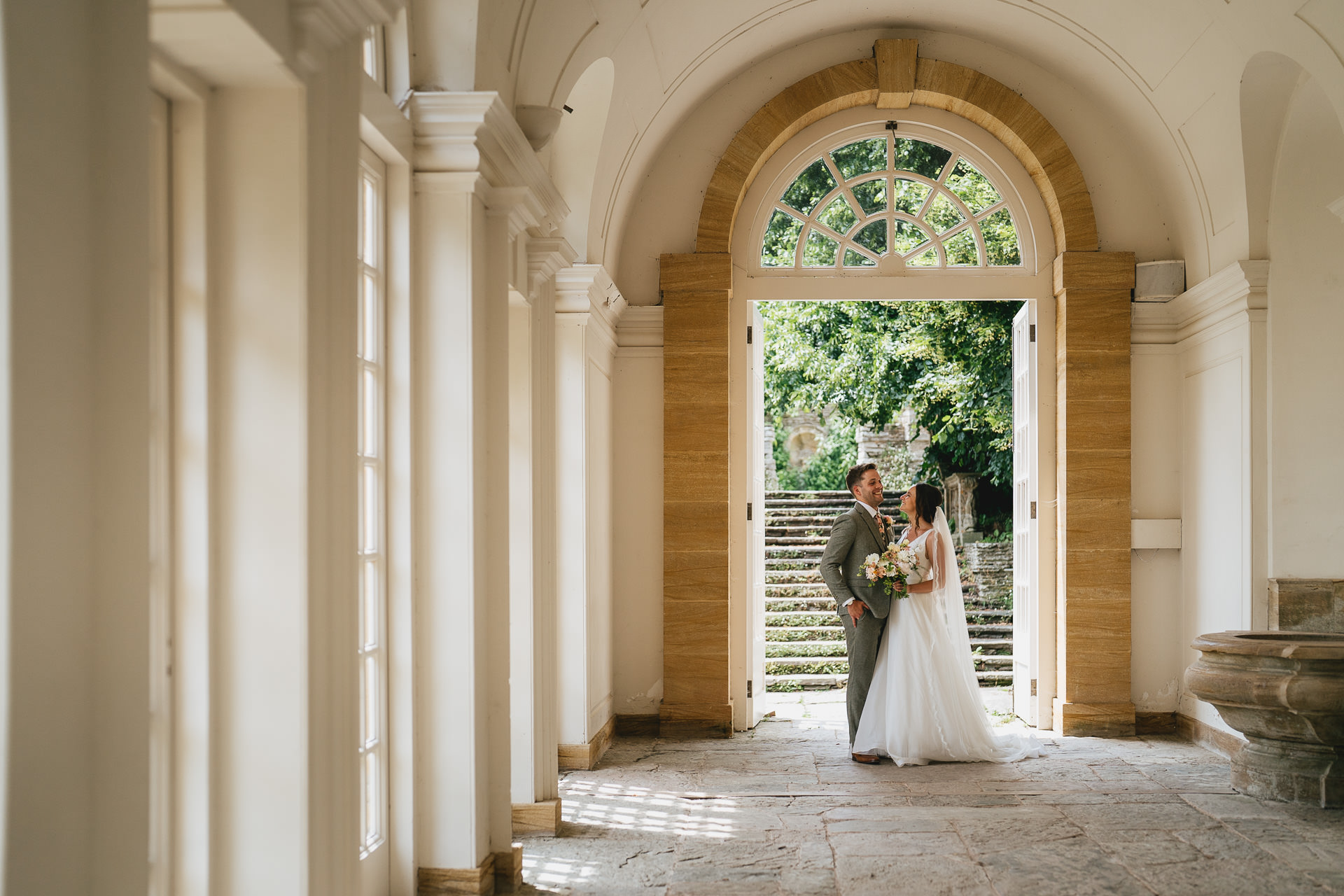 A couple chatting together on their wedding day in the orangery at Hestercombe in Somerset