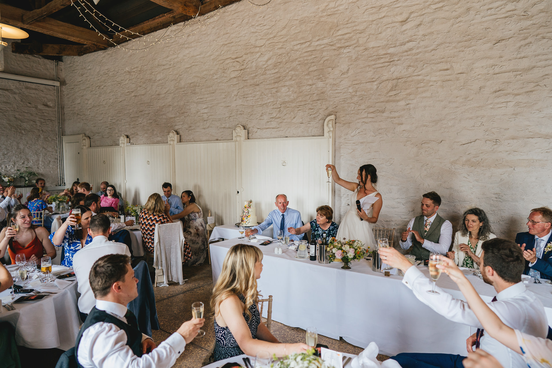 Bride raising a toast during speeches at a Hestercombe wedding reception