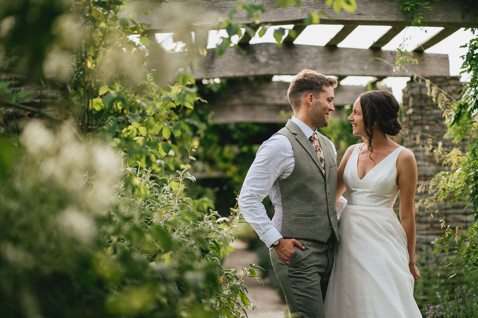 A bride and groom cuddling in beautiful gardens