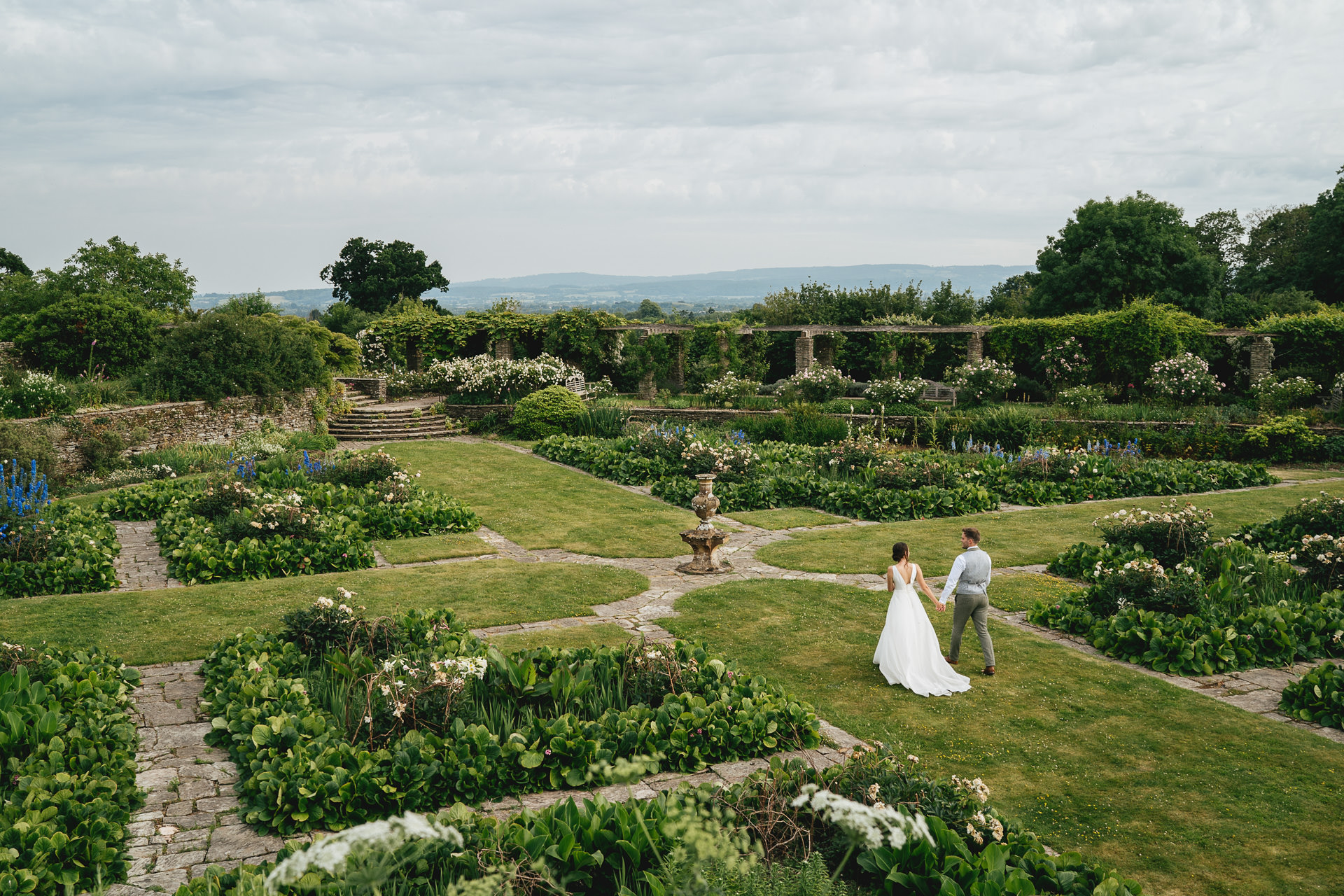 A bride and groom walking through Hestercombe Gardens with incredible views over Somerset