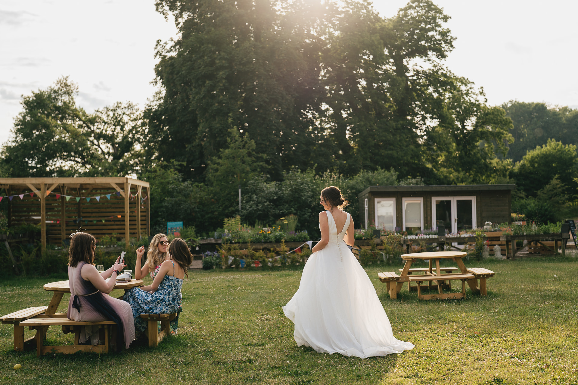 A bride in a wedding dress walking across the grass in evening sunlight at a Hestercombe Gardens wedding reception
