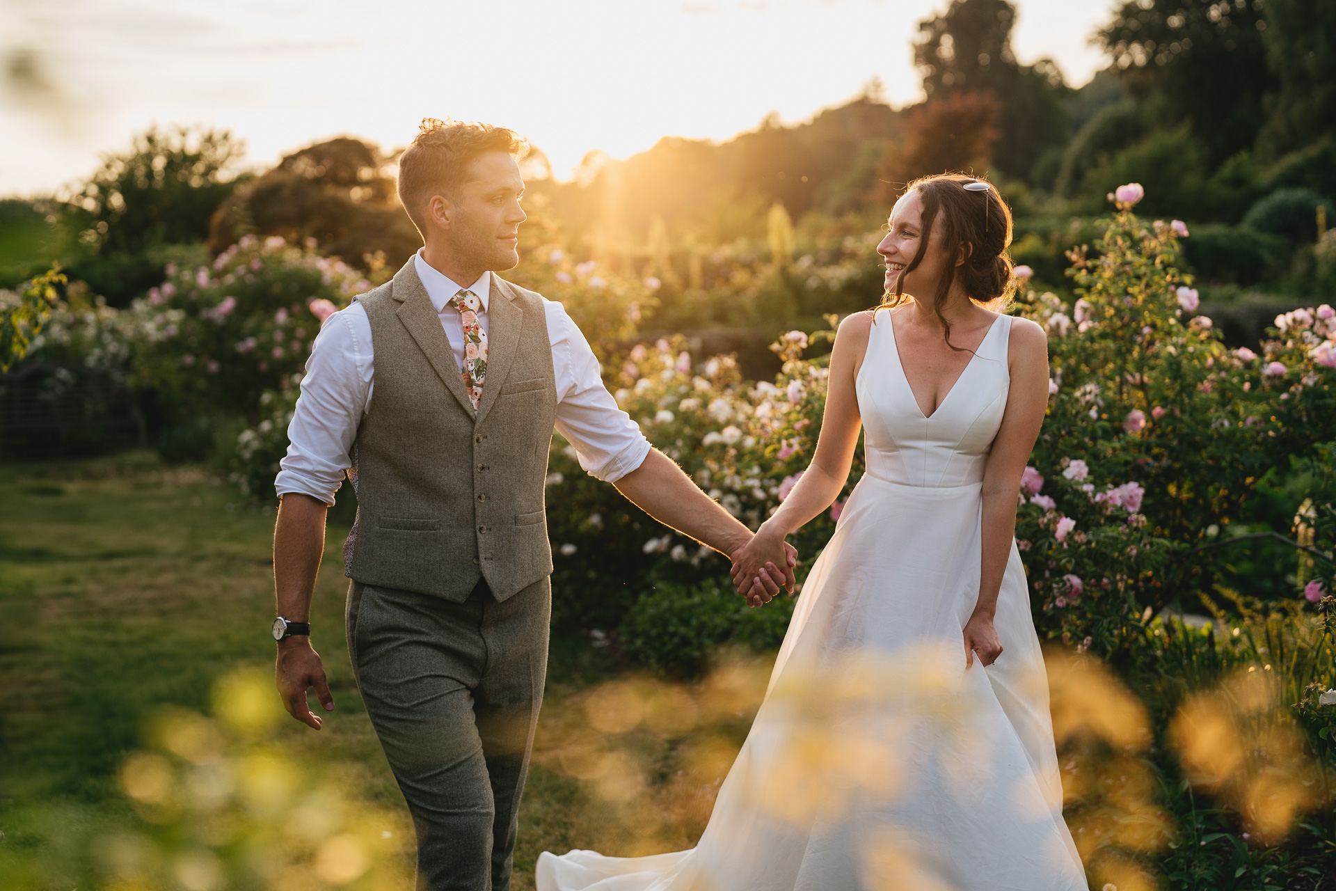 A couple in beautiful evening sunlight, walking through Hestercombe Gardens on their wedding day