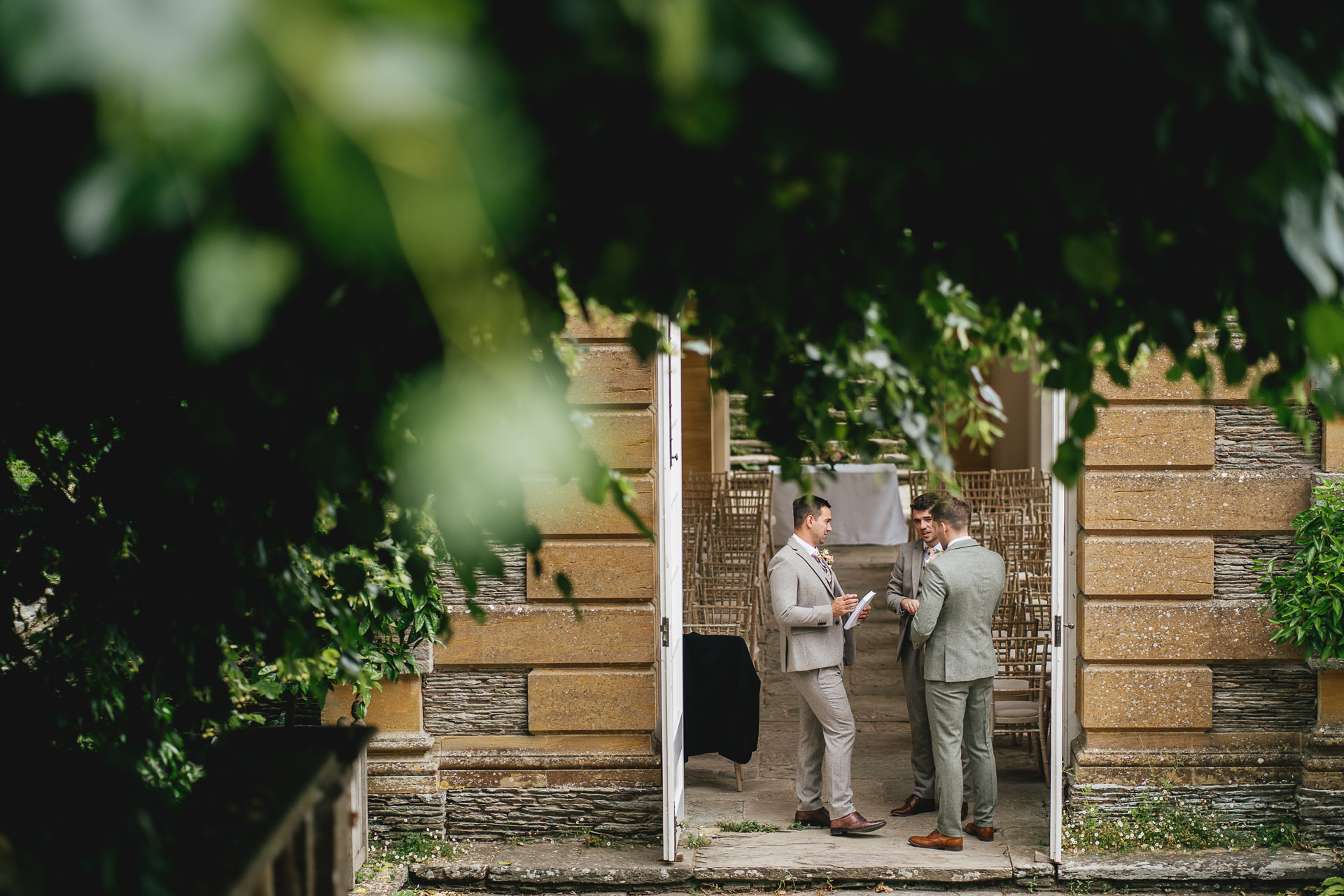 A groom and groomsmen standing together at the entrance to the orangery at Hestercombe Gardens