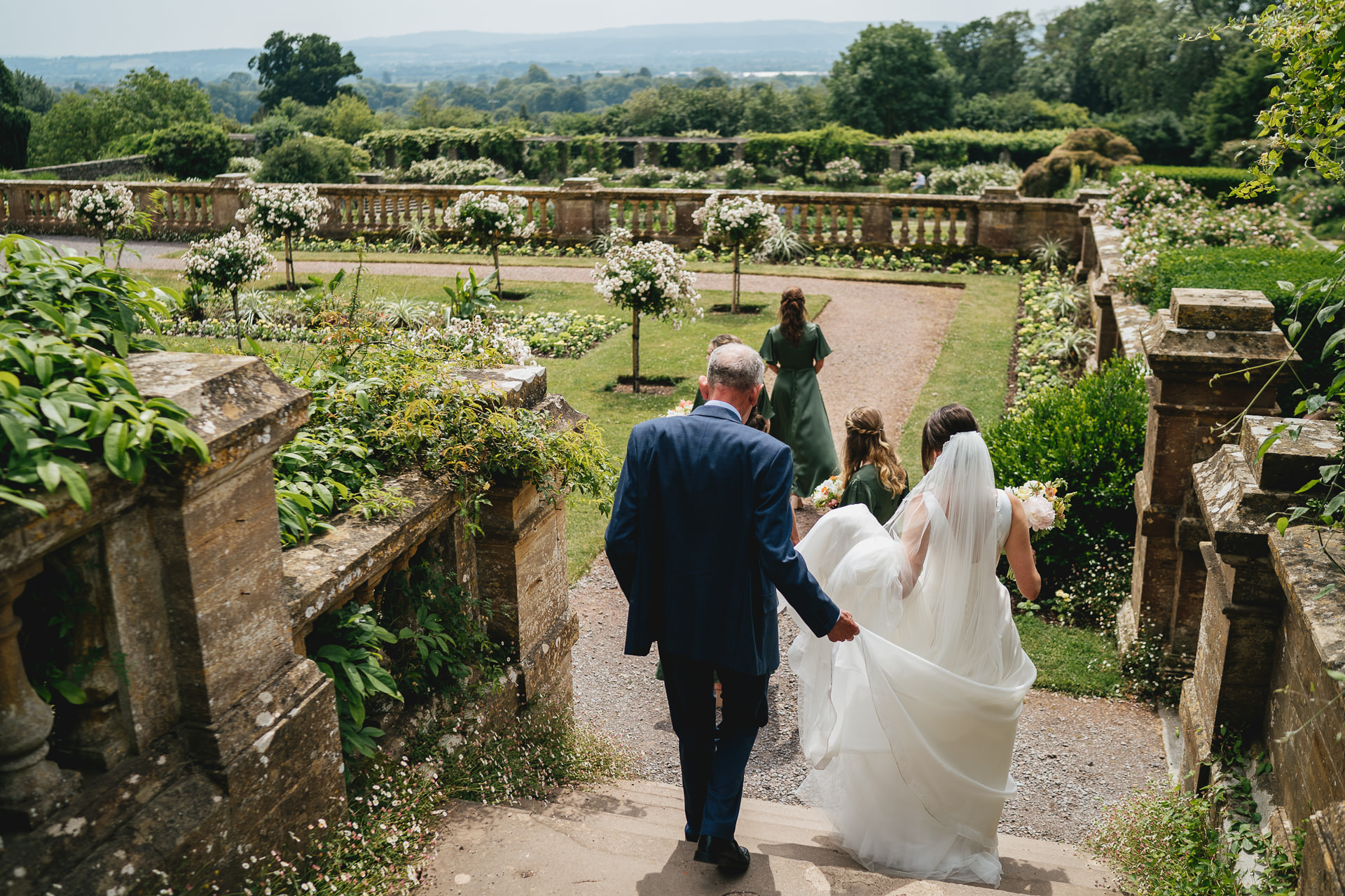 A bride walking down some steps at Hestercombe Gardens with views across Somerset